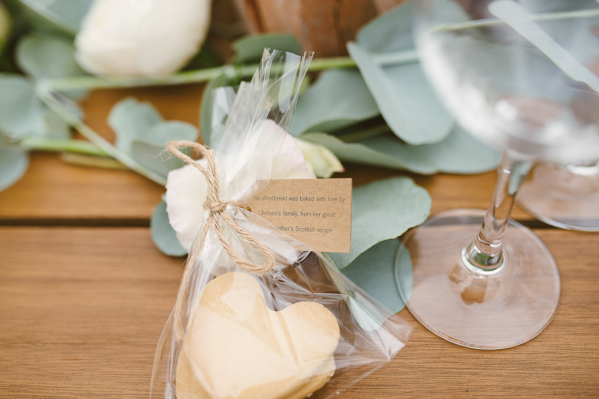 home made love-heart shaped shortbread gift wrapped for guests on a wooden wedding table