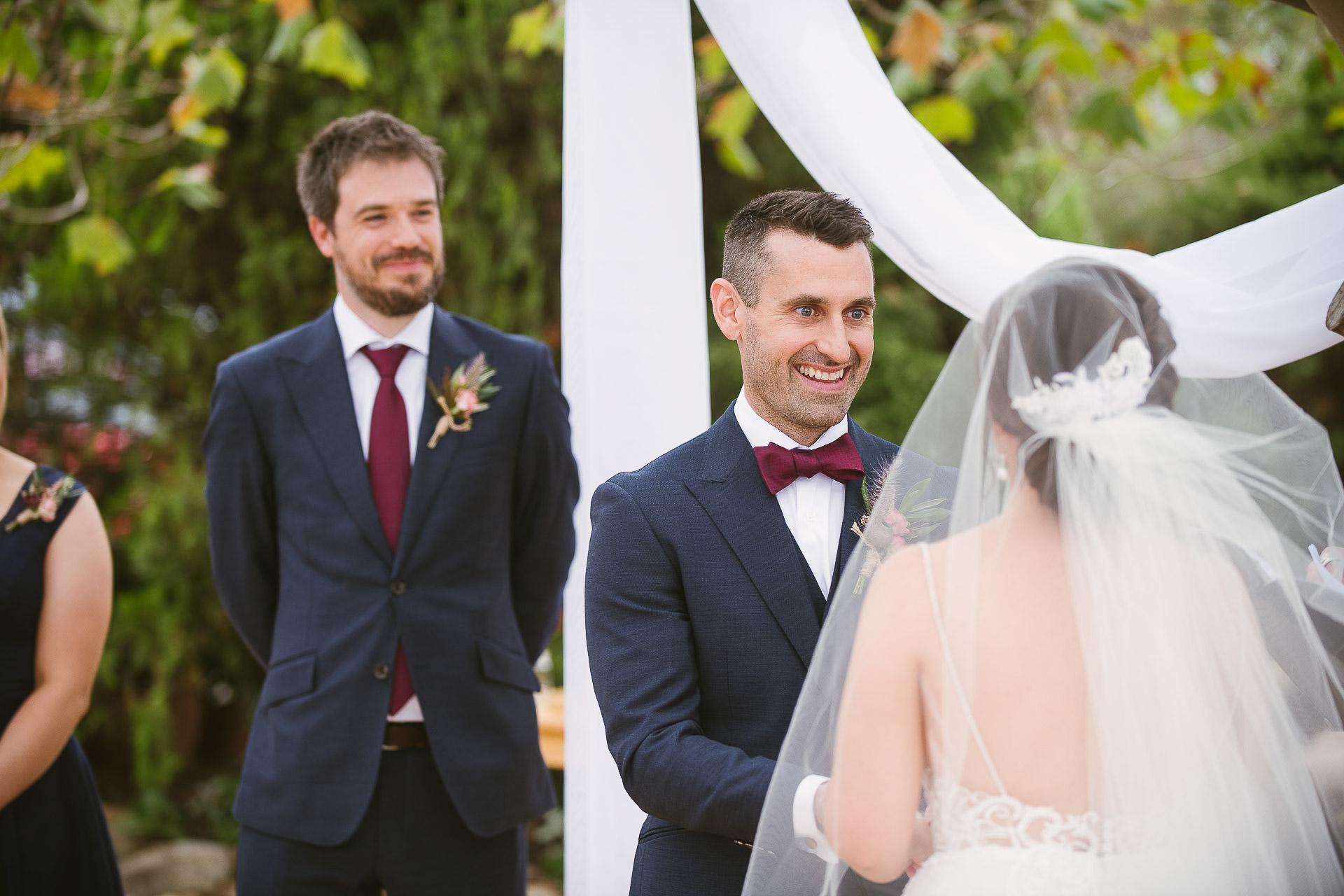 groom smiling over brides shoulder during ceremony at winery wedding