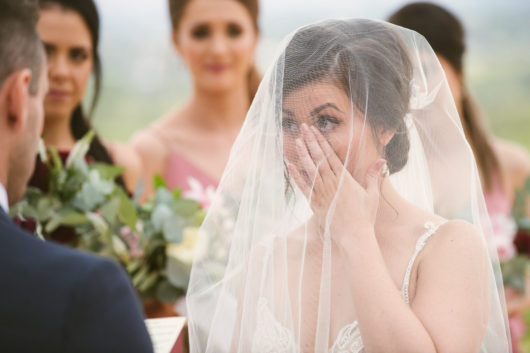 bride wiping tear from her cheek during emotional wedding ceremony