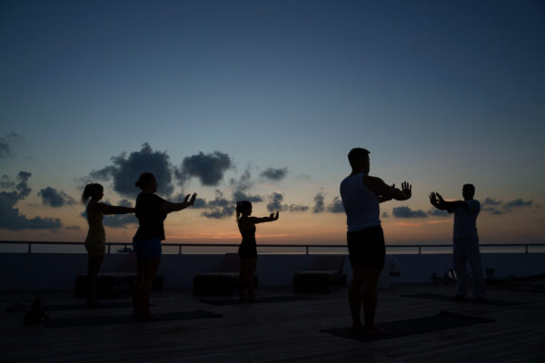 Conference attendees celebrating during a sunrise yoga session on a liveaboard deck in the Maldives