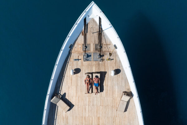 Aerial view of couple in bathers sunbaking on Scubaspa luxury liveaboard vessel bow and sun deck in the Maldives